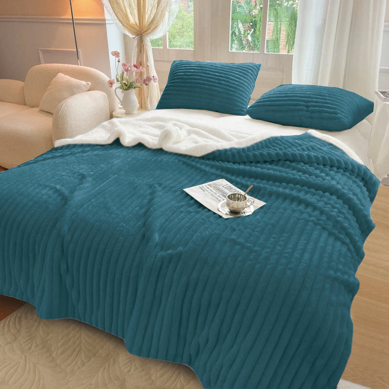 A Stripe Flannel Sherpa Blanket/Comforter Set on a bed with a striped pattern, displayed in a room setting with accompanying pillows and a book.